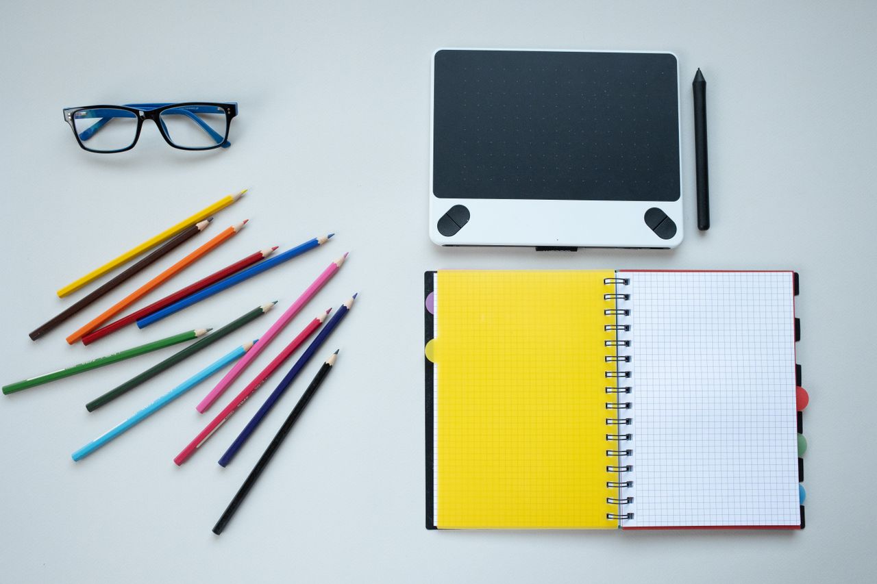 hero-img Flat lay of a creative workspace featuring colored pencils, notebook, and graphic tablet.